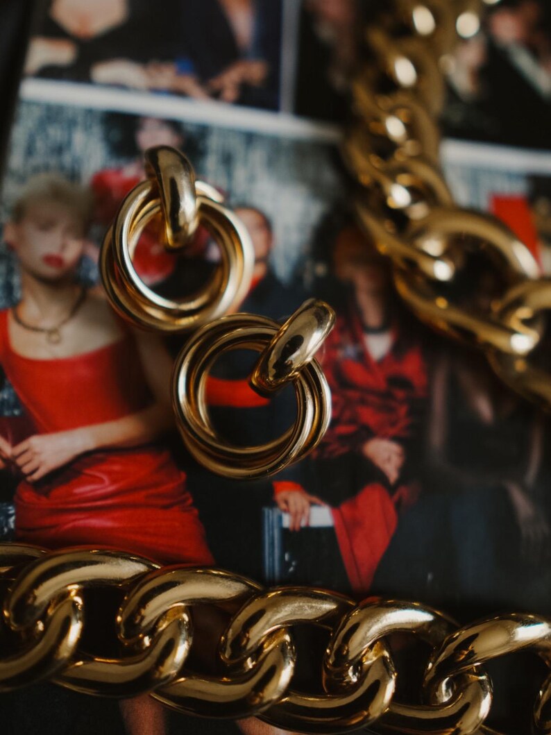 vintage 1990s drapers & Damons gold interlocking ring sculptural earrings styled along other vintage gold jewelry pieces.