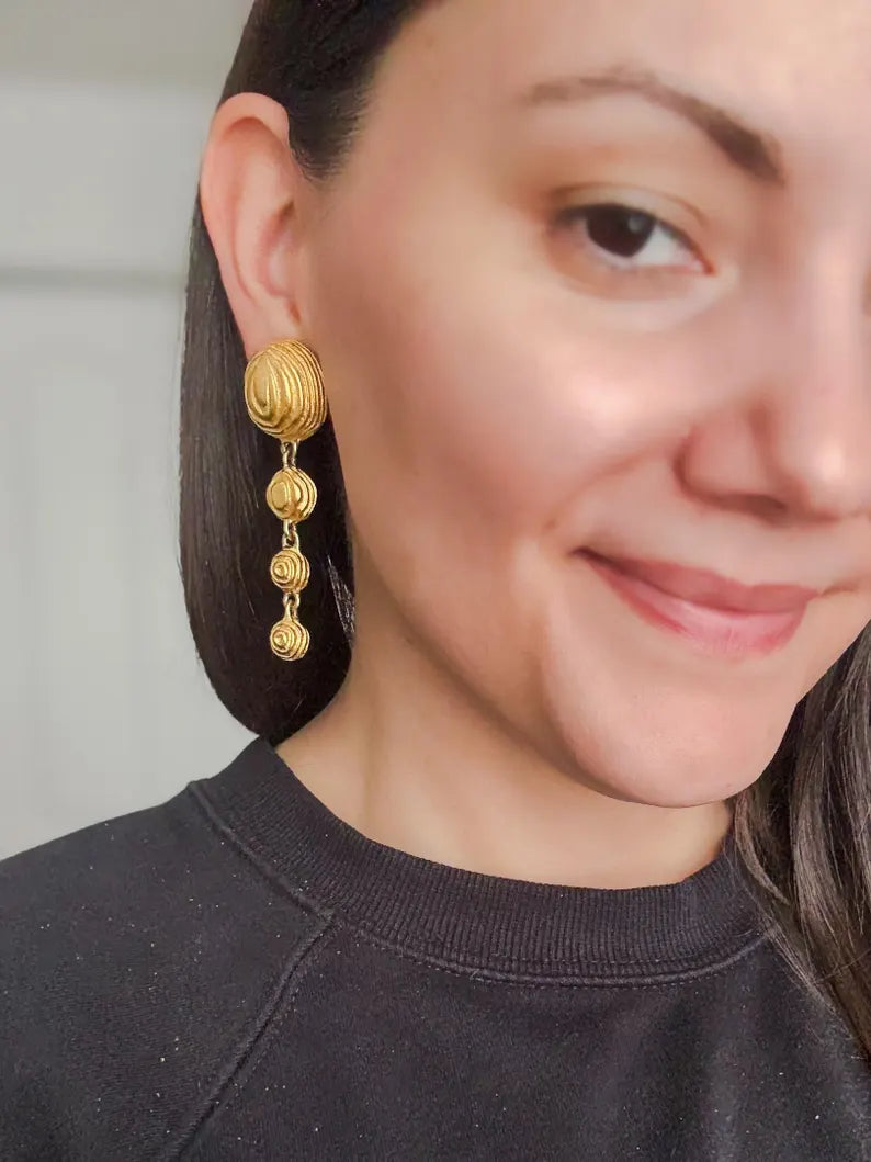 A close-up of a model wearing the vintage designer matte gold sculptural dome shaped crop earrings.
