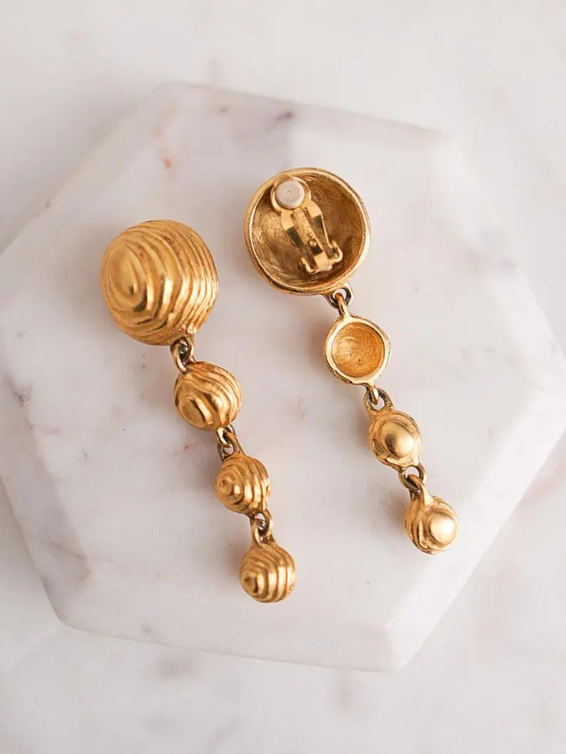 A pair of vintage designer gold-toned drop earrings with matte gold textured dome elements.