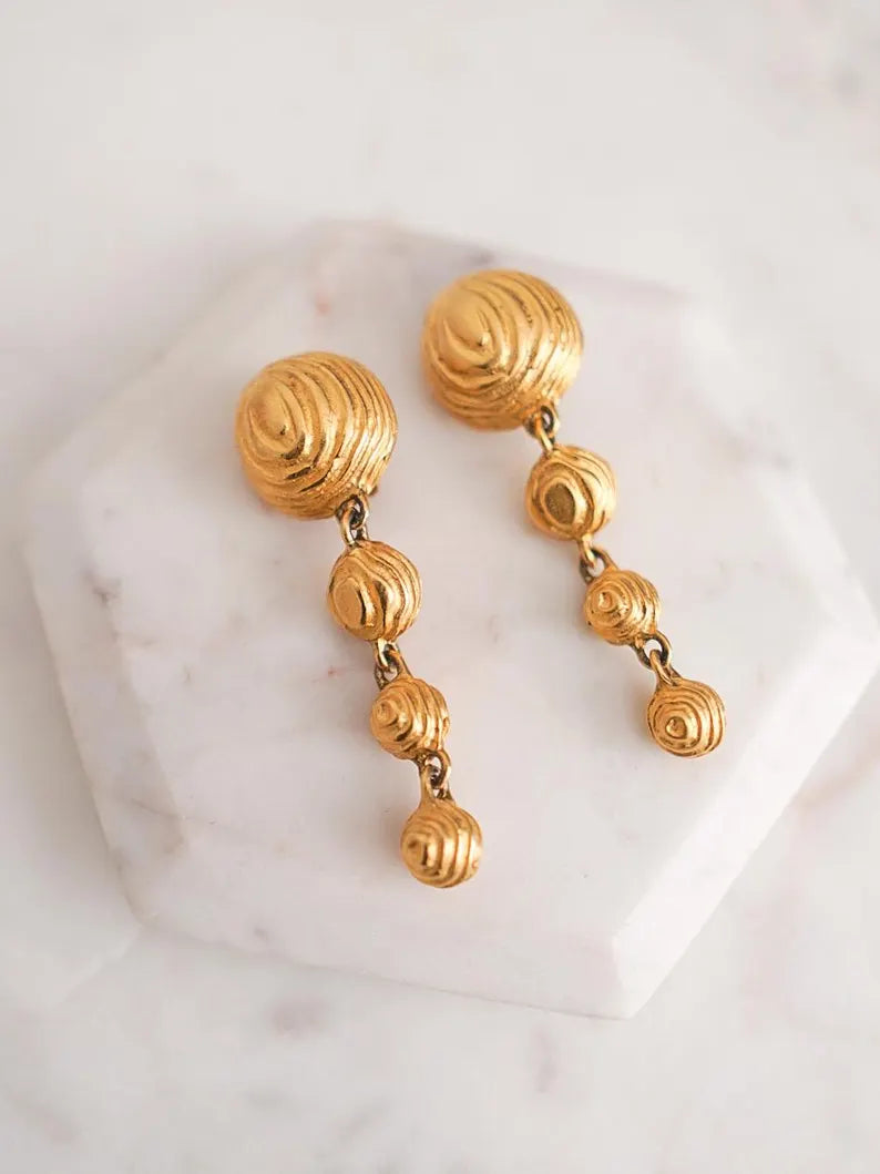 A pair of vintage designer gold drop earrings with textured dome shaped charms.