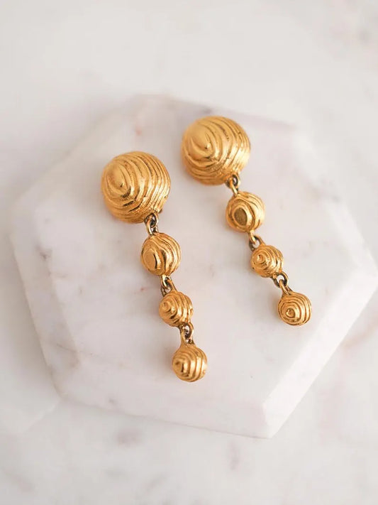 A pair of vintage designer gold drop earrings with textured dome shaped charms.
