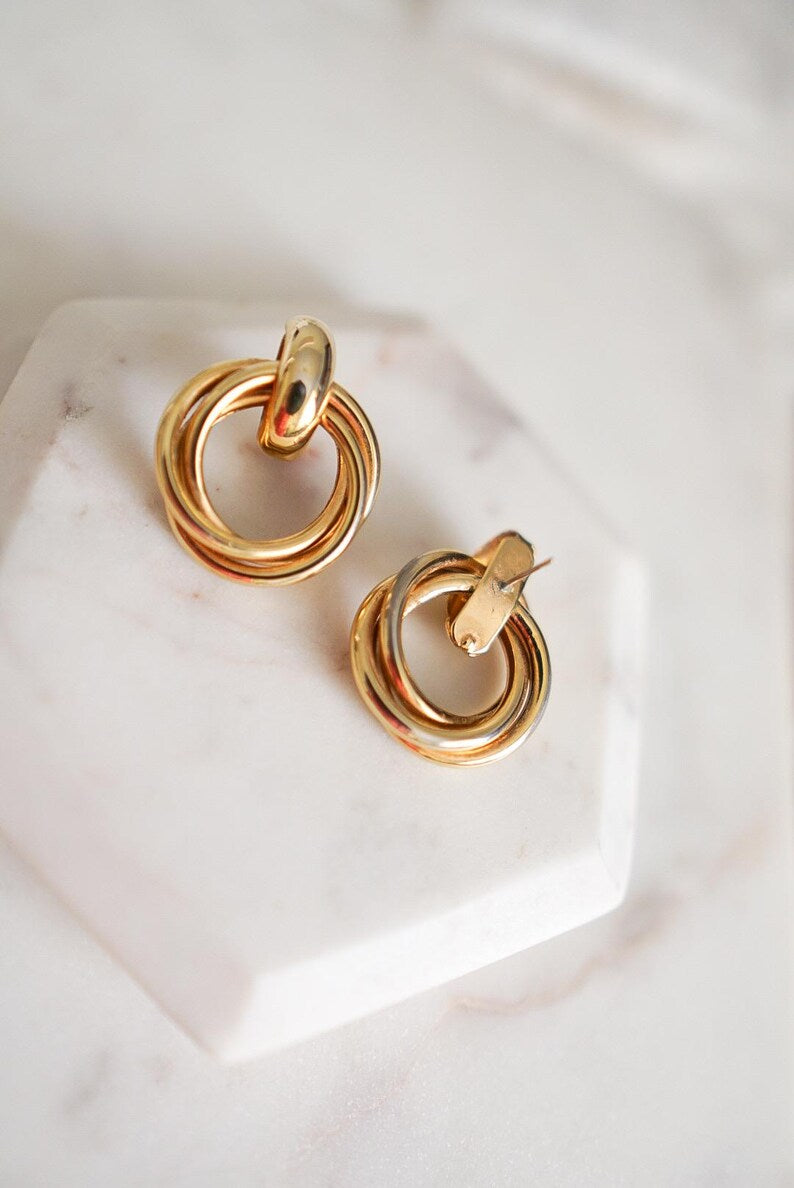 A pair of 90s vintage gold-toned triple-ring hoop earrings with a post back closure.