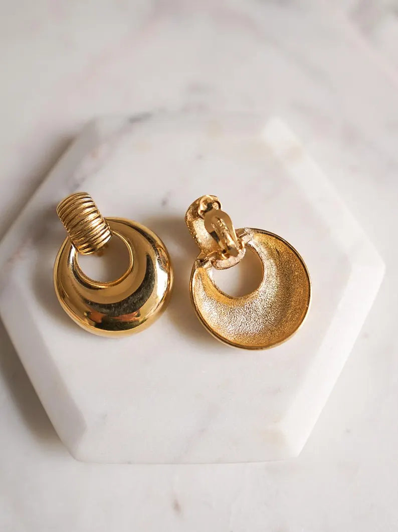 A pair of gold-toned hoop earrings with textured and ribbed finish.
